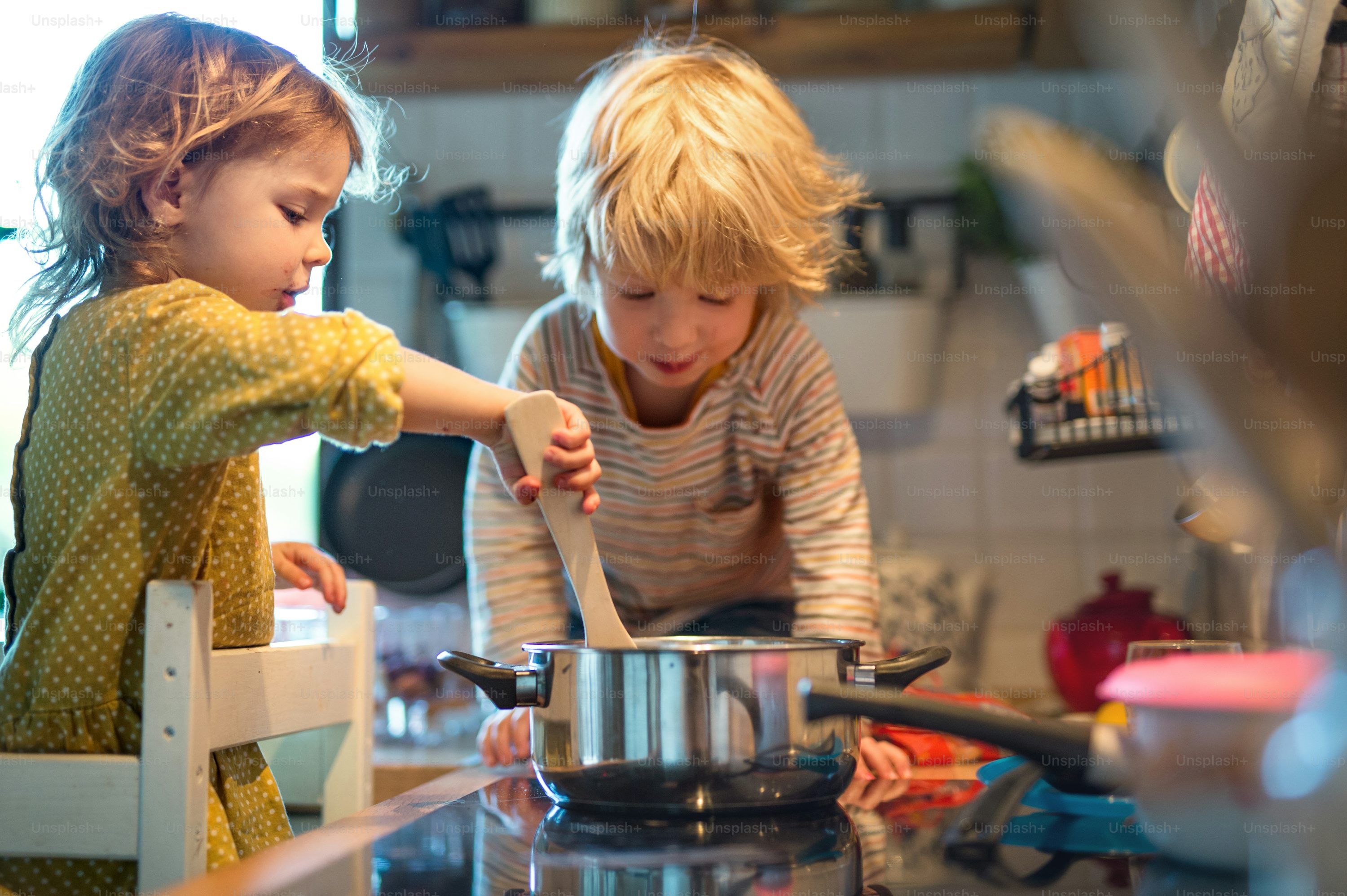 Happy small boy and girl indoors in kitchen